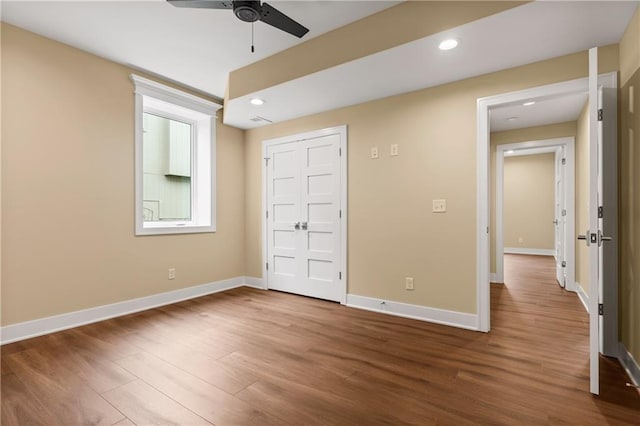 unfurnished bedroom featuring a closet, dark hardwood / wood-style flooring, and ceiling fan