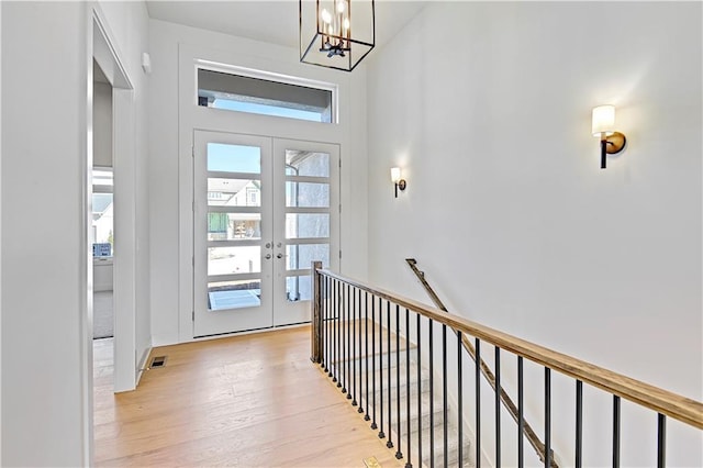 interior space featuring a notable chandelier, french doors, and light wood-type flooring