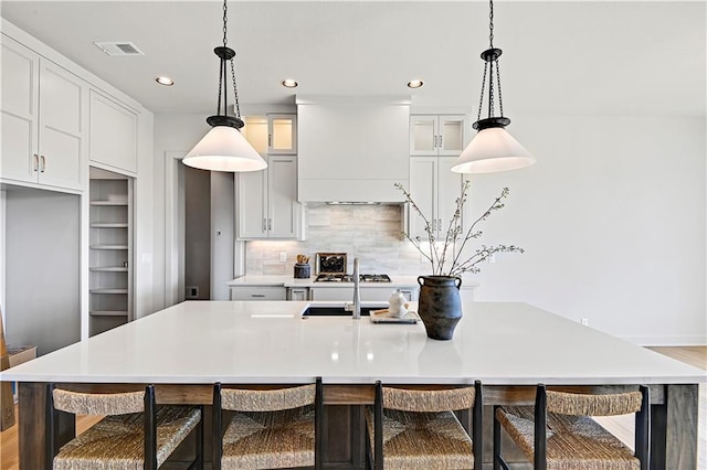 kitchen featuring pendant lighting, a large island, a breakfast bar, and custom range hood