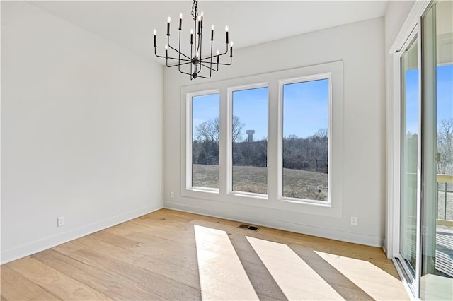 unfurnished dining area featuring an inviting chandelier and light wood-type flooring