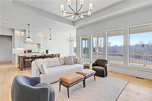 living room featuring an inviting chandelier, sink, and light wood-type flooring