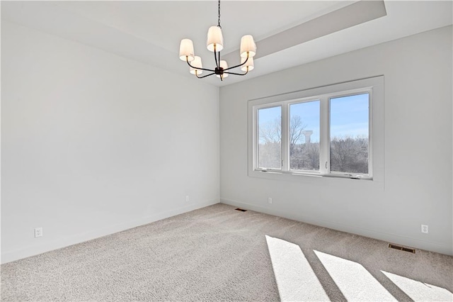 carpeted empty room featuring a chandelier and a raised ceiling