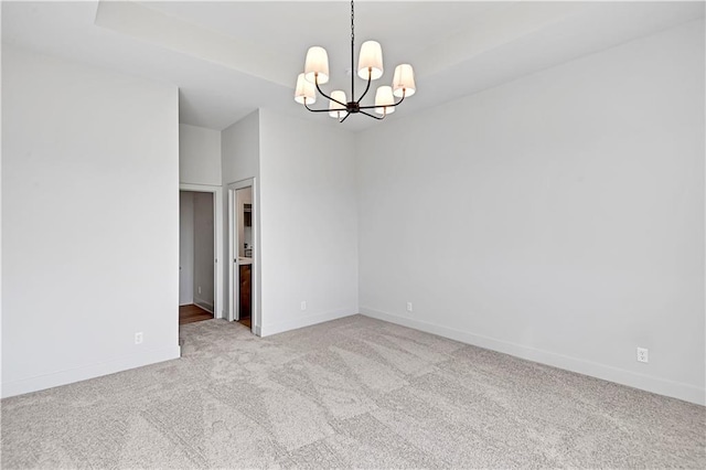 carpeted spare room featuring a chandelier