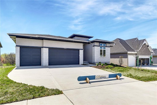 22051 W 100th Ter, Lenexa, KS 66220 - prairie-style home featuring concrete driveway, an attached garage, brick siding, and stucco siding