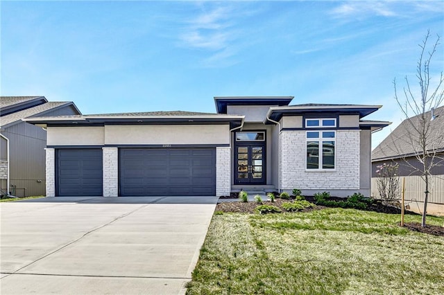 22051 W 100th Ter, Lenexa, KS 66220 - prairie-style home with a garage, driveway, stucco siding, french doors, and brick siding