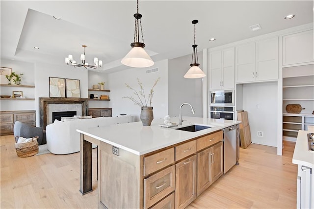 22051 W 100th Ter, Lenexa, KS 66220 - kitchen featuring a sink, light wood-type flooring, stainless steel appliances, light countertops, and a center island with sink