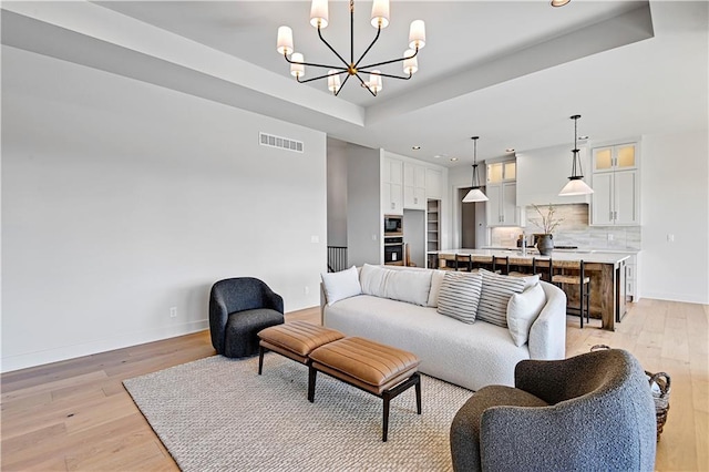 22051 W 100th Ter, Lenexa, KS 66220 - living area featuring light wood-type flooring, a chandelier, baseboards, recessed lighting, and a tray ceiling