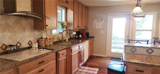 kitchen with dark stone countertops, dark hardwood / wood-style flooring, wall chimney exhaust hood, and decorative light fixtures