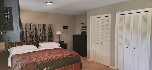 bedroom with light colored carpet and two closets