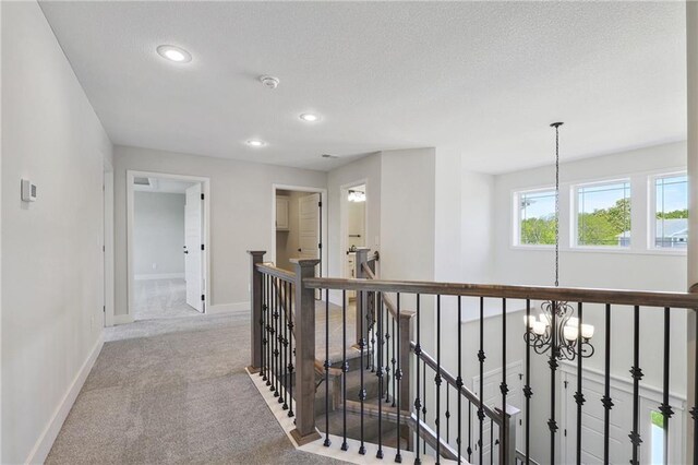 hallway with an inviting chandelier and carpet flooring