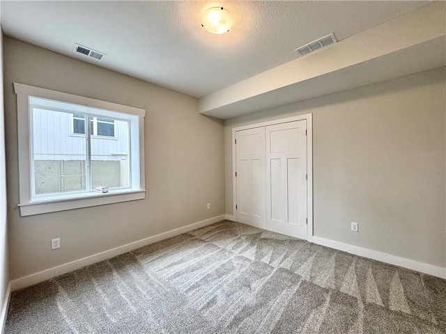 unfurnished bedroom with a closet, carpet flooring, and a textured ceiling