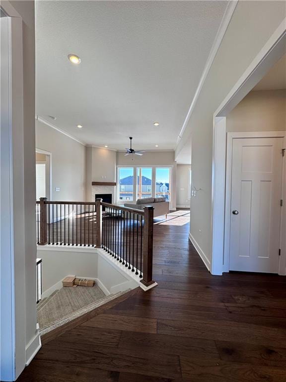 hallway featuring an upstairs landing, ornamental molding, baseboards, and wood finished floors