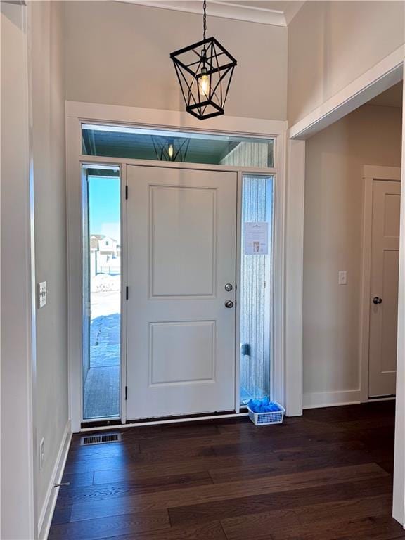 entryway featuring visible vents, baseboards, dark wood-type flooring, and ornamental molding