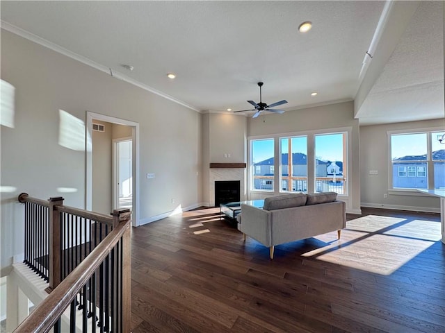 living room featuring ceiling fan, crown molding, dark hardwood / wood-style floors, and a fireplace