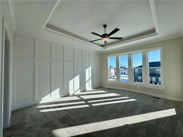 carpeted empty room with ornamental molding, ceiling fan, and a tray ceiling