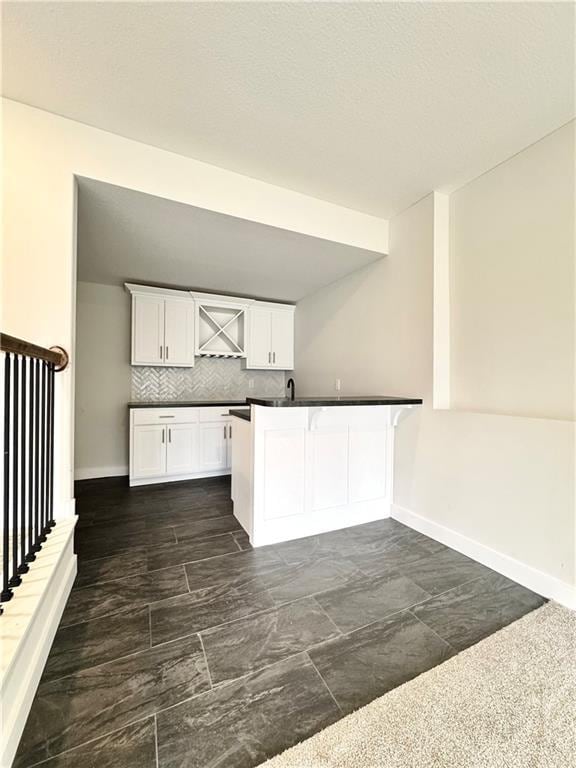 kitchen with a breakfast bar area, white cabinets, backsplash, and kitchen peninsula