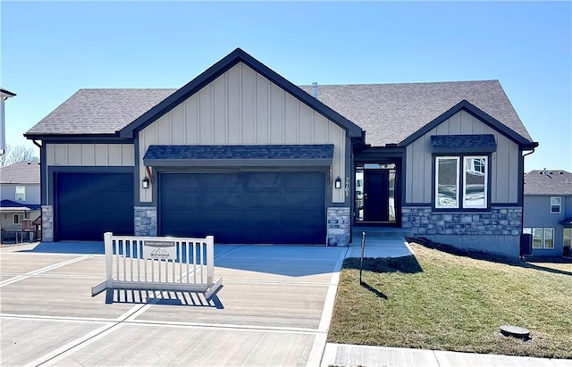 view of front of home with stone siding, an attached garage, driveway, and a front yard