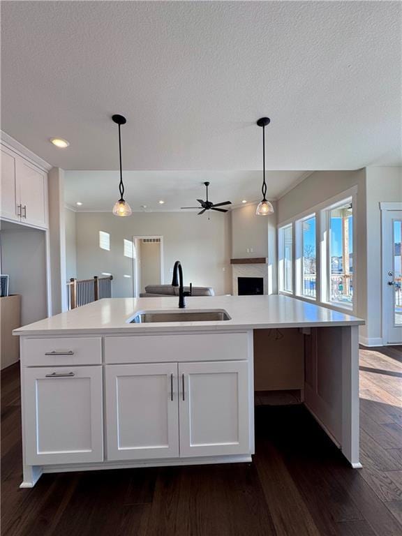 kitchen featuring hanging light fixtures, open floor plan, dark wood-style flooring, and a sink