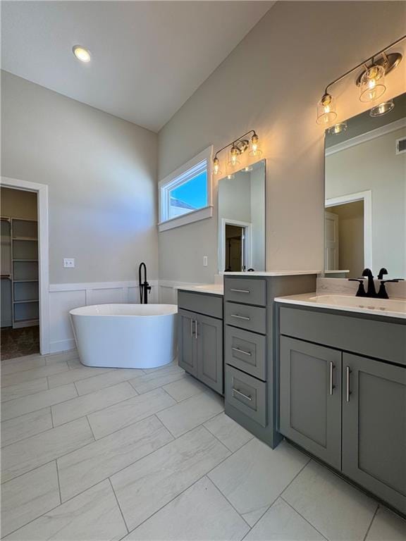 full bath with a wainscoted wall, a freestanding bath, vanity, and visible vents