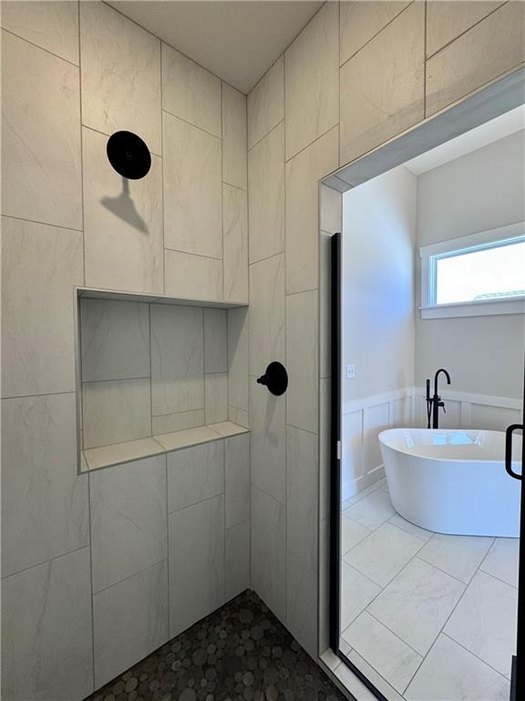 bathroom with a tile shower, wainscoting, and a freestanding bath