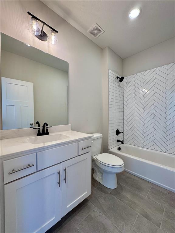 bathroom featuring visible vents, toilet, shower / washtub combination, and vanity