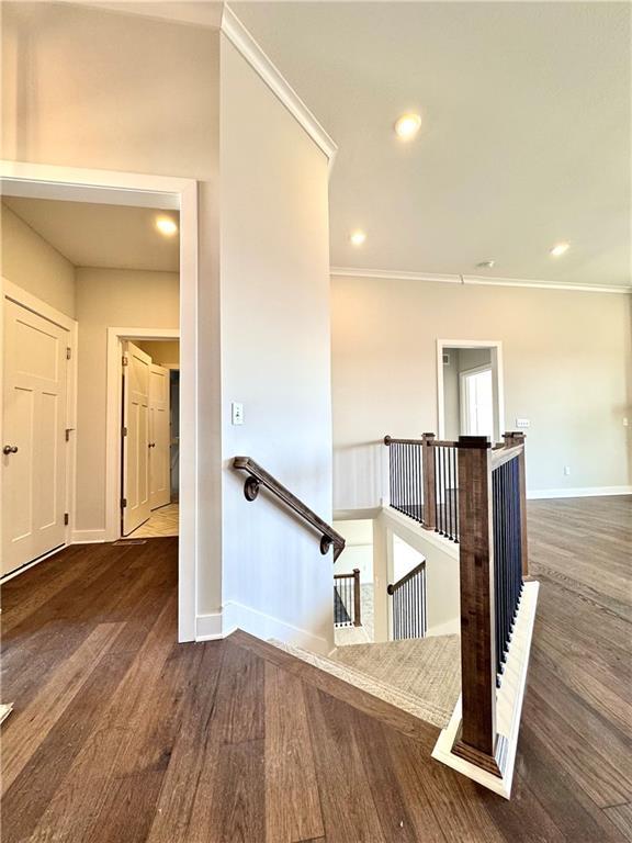 stairway with crown molding, recessed lighting, wood finished floors, and baseboards