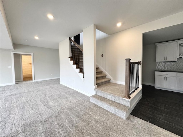 interior space with recessed lighting, dark carpet, stairs, and baseboards