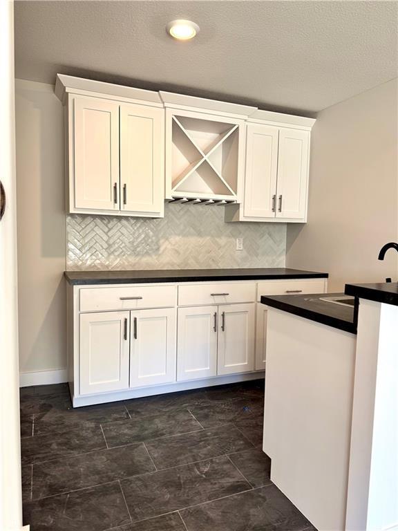 kitchen featuring white cabinetry, dark countertops, and backsplash