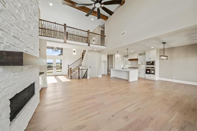 unfurnished living room with a fireplace, a high ceiling, light hardwood / wood-style floors, and sink