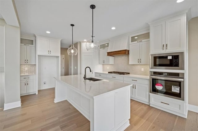 kitchen featuring white cabinets, custom range hood, stainless steel appliances, and sink