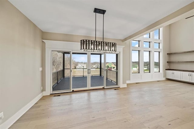 unfurnished dining area featuring an inviting chandelier and light wood-type flooring