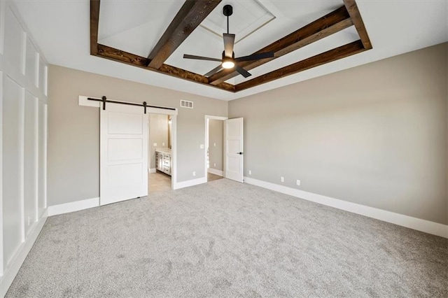 unfurnished bedroom featuring a barn door, light colored carpet, and connected bathroom