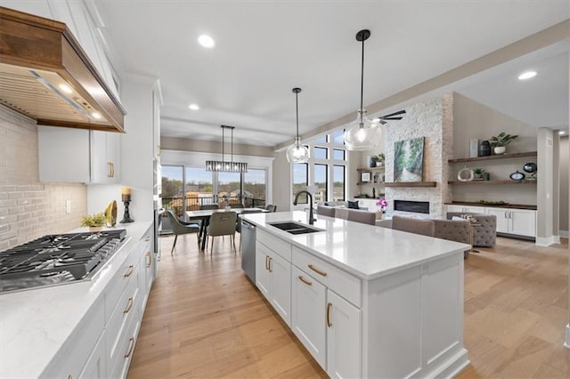 kitchen with custom range hood, a sink, appliances with stainless steel finishes, and light wood-style floors