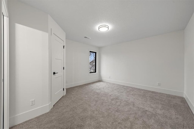 carpeted spare room featuring baseboards, a textured ceiling, and visible vents
