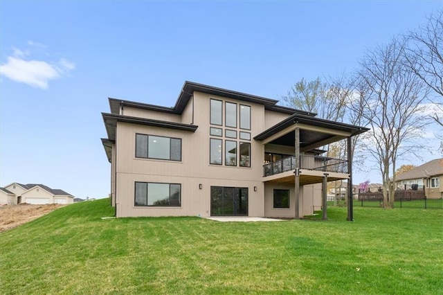 rear view of property featuring a balcony, fence, a lawn, and a patio area