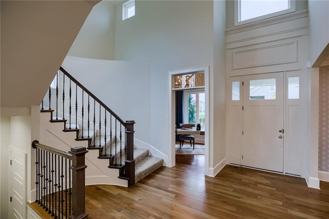 entryway featuring wood-type flooring and a high ceiling