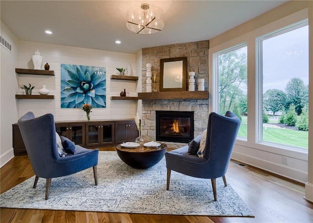 living area with a chandelier, wood-type flooring, and a fireplace