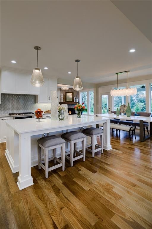 kitchen featuring decorative light fixtures, tasteful backsplash, hardwood / wood-style flooring, and white cabinetry