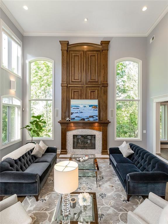 living room with a healthy amount of sunlight, a large fireplace, and ornamental molding