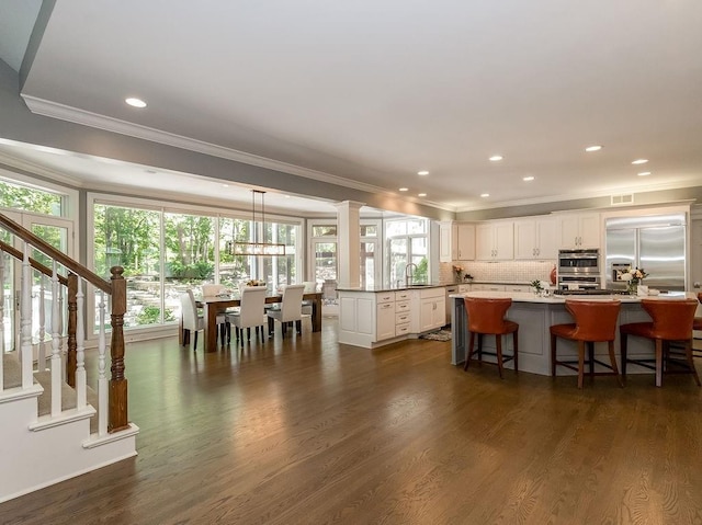 kitchen featuring a kitchen island, pendant lighting, white cabinets, dark hardwood / wood-style flooring, and stainless steel appliances