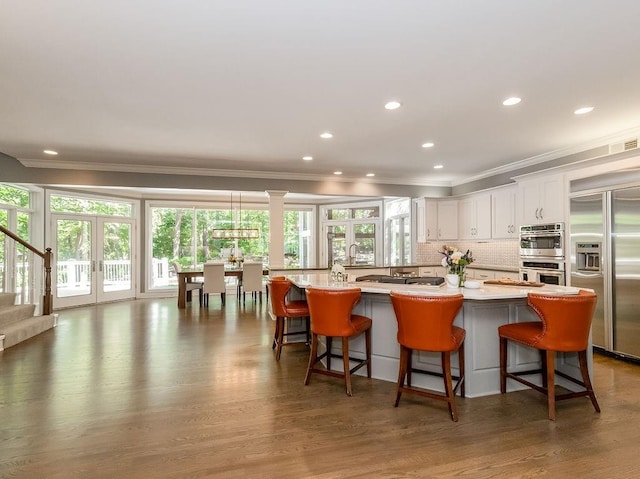 kitchen with french doors, a breakfast bar area, decorative light fixtures, appliances with stainless steel finishes, and white cabinets