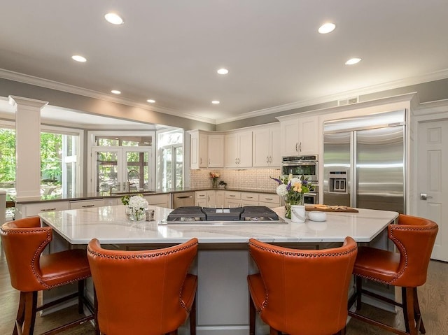 kitchen featuring a kitchen bar, stainless steel appliances, a wealth of natural light, and white cabinets