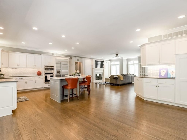 kitchen featuring a center island, stainless steel appliances, a breakfast bar, and white cabinets