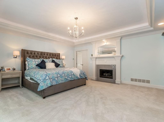 carpeted bedroom with crown molding, a fireplace, a tray ceiling, and a notable chandelier