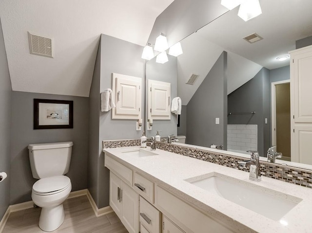 bathroom featuring toilet, tasteful backsplash, vaulted ceiling, vanity, and hardwood / wood-style flooring