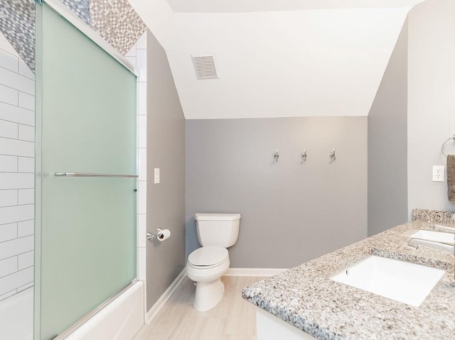 full bathroom with bath / shower combo with glass door, vanity, toilet, and vaulted ceiling