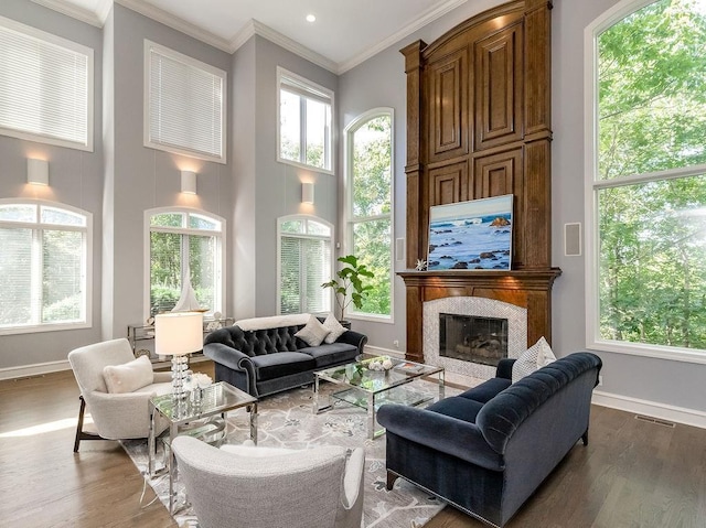 sitting room featuring a premium fireplace, ornamental molding, a towering ceiling, and hardwood / wood-style floors