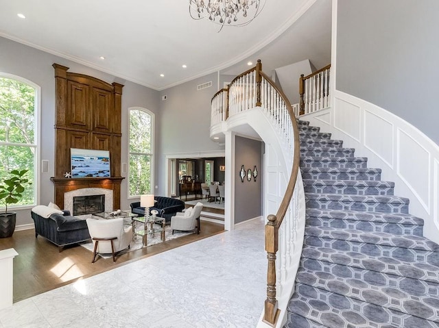 stairway featuring a notable chandelier, crown molding, and a towering ceiling