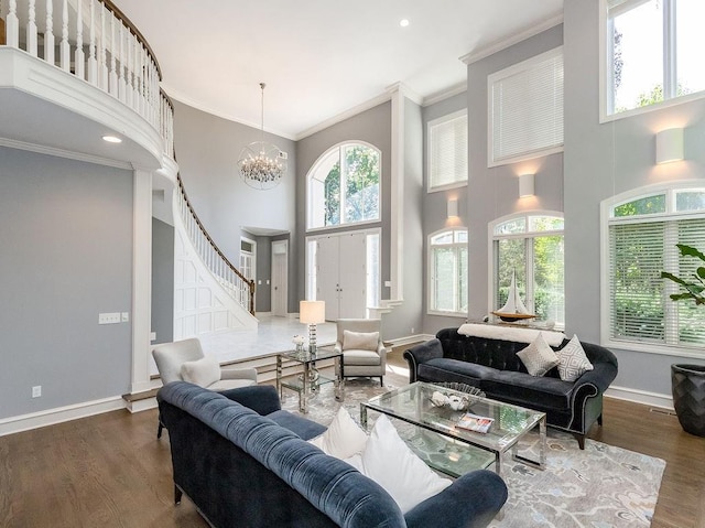 living room featuring dark wood-type flooring, a towering ceiling, crown molding, and a chandelier