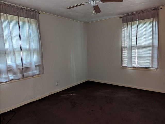 spare room featuring dark colored carpet and ceiling fan